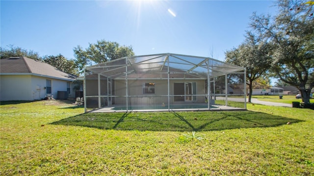 back of house with a lanai and a lawn