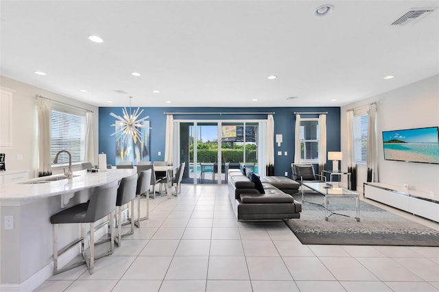 living room featuring light tile patterned flooring, sink, and a notable chandelier