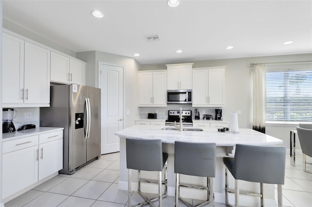 kitchen with appliances with stainless steel finishes, white cabinetry, and light tile patterned floors