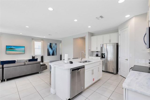 kitchen with white cabinetry, sink, stainless steel appliances, and an island with sink