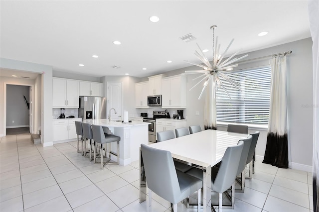 dining space with sink, light tile patterned flooring, and an inviting chandelier