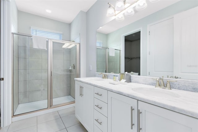 bathroom featuring a shower with shower door, dual bowl vanity, and tile patterned floors