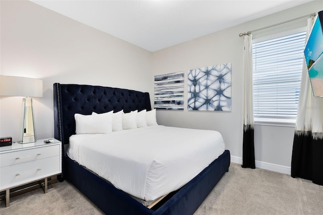 bedroom with light carpet, baseboards, and multiple windows