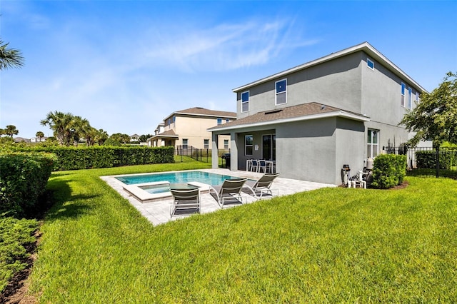 rear view of house with a lawn, a patio, and a swimming pool with hot tub