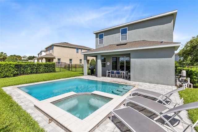 view of pool with a yard, a pool with connected hot tub, fence, and a patio