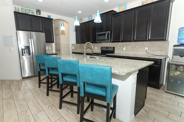 kitchen featuring appliances with stainless steel finishes, sink, hanging light fixtures, and a center island with sink