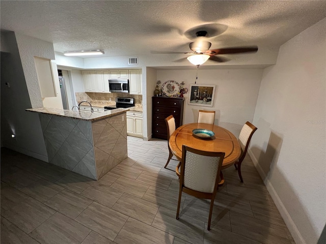 dining space featuring visible vents, ceiling fan, a textured ceiling, and baseboards