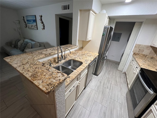 kitchen with a peninsula, appliances with stainless steel finishes, visible vents, and a sink