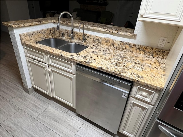 kitchen with dishwasher, a peninsula, a sink, and light stone countertops