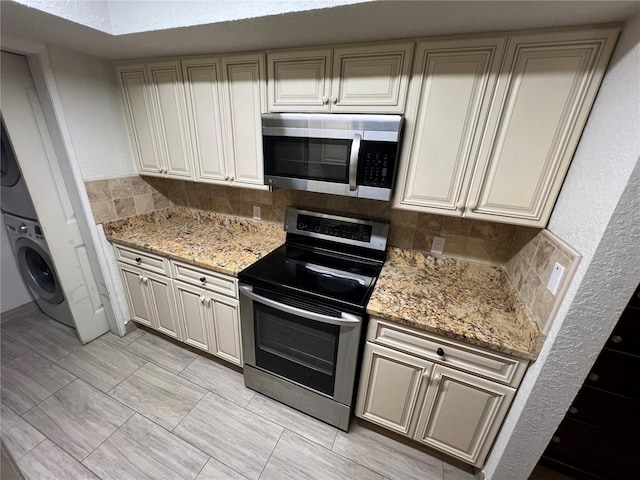 kitchen with appliances with stainless steel finishes, decorative backsplash, light stone counters, and stacked washer and clothes dryer