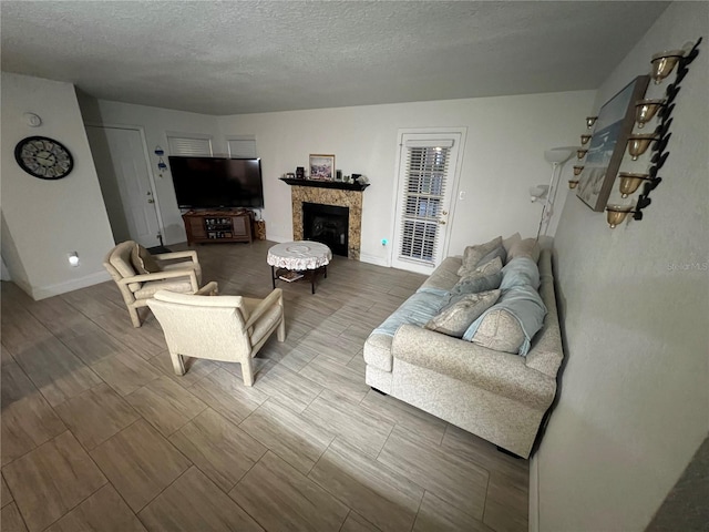 living room with wood tiled floor, a fireplace, baseboards, and a textured ceiling