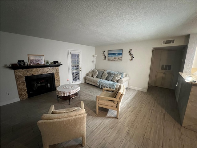 living room featuring baseboards, visible vents, a premium fireplace, wood tiled floor, and a textured ceiling