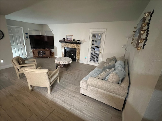 living room with a glass covered fireplace, baseboards, and wood tiled floor