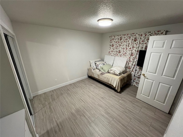 unfurnished bedroom with light wood-style flooring, a textured ceiling, and baseboards