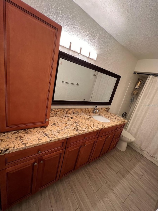 full bathroom with shower / tub combo, a textured wall, toilet, a textured ceiling, and vanity