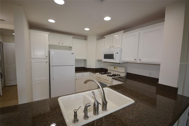 kitchen with sink, white appliances, white cabinets, and hardwood / wood-style flooring