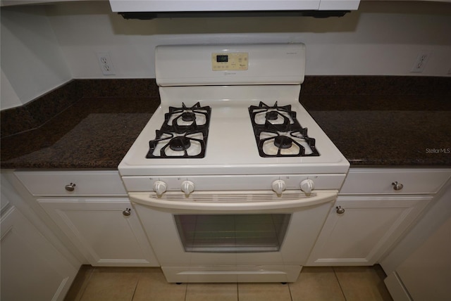 kitchen featuring dark stone countertops, gas range gas stove, and light tile patterned flooring