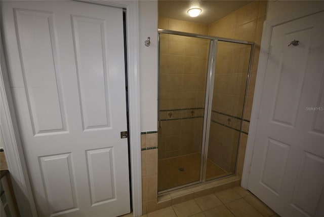 bathroom with tile patterned flooring and a shower with shower door