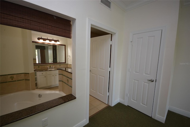 bathroom featuring a bathing tub, crown molding, vanity, and tile patterned floors