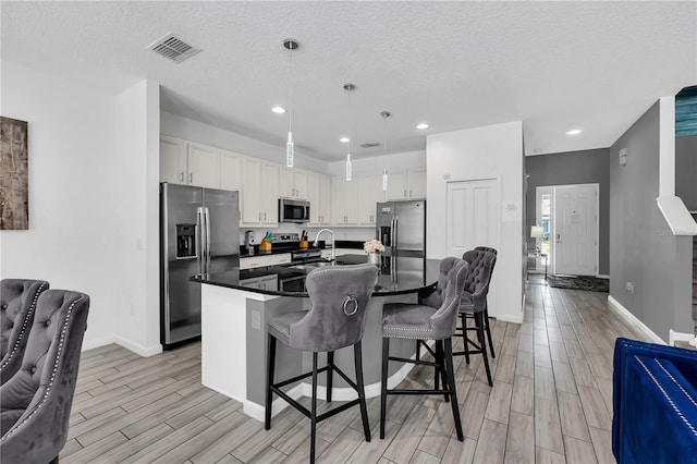 kitchen featuring a breakfast bar, white cabinetry, a textured ceiling, and appliances with stainless steel finishes