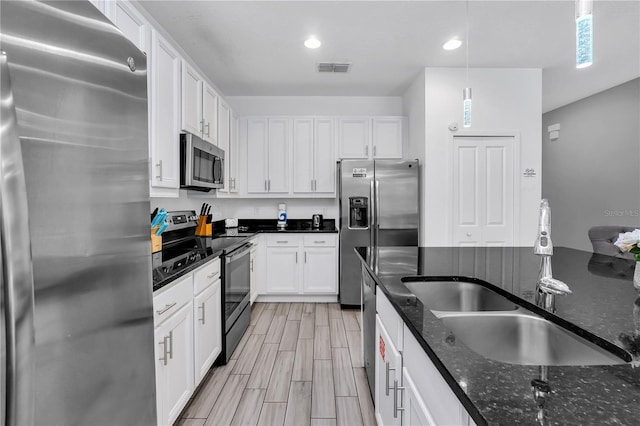 kitchen with sink, dark stone countertops, decorative light fixtures, stainless steel appliances, and white cabinets