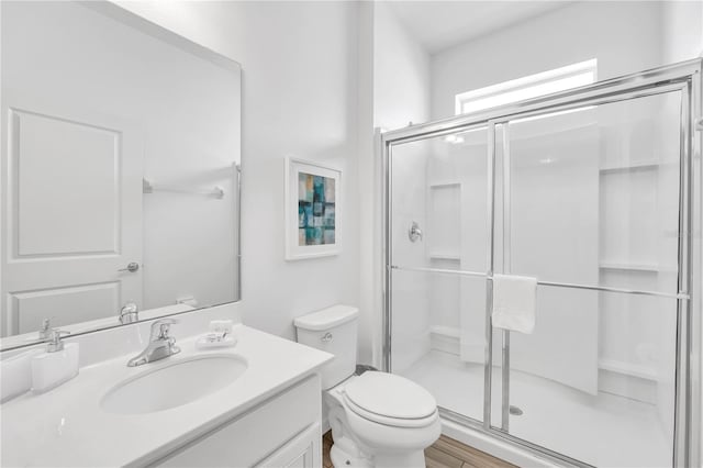 bathroom with wood-type flooring, vanity, walk in shower, and toilet