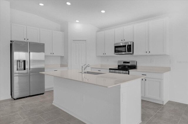 kitchen featuring stainless steel appliances, light tile patterned floors, white cabinets, a center island with sink, and sink