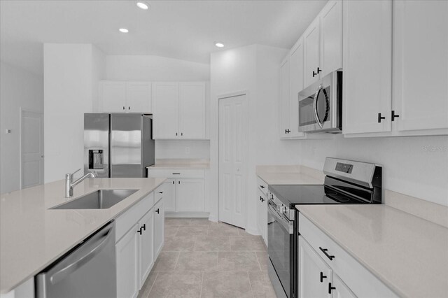 kitchen featuring stainless steel appliances, white cabinets, light tile patterned floors, sink, and vaulted ceiling