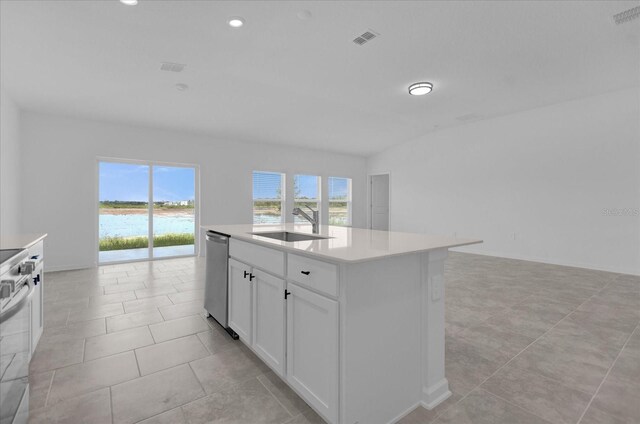 kitchen with white cabinets, a kitchen island with sink, a water view, light tile patterned floors, and stainless steel appliances