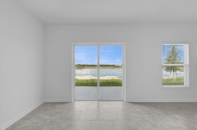 unfurnished room with a water view and light tile patterned floors