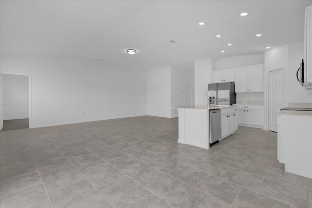 kitchen with appliances with stainless steel finishes, an island with sink, light tile patterned floors, and white cabinets