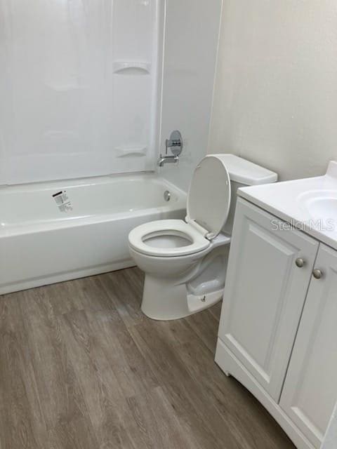 full bathroom with vanity, toilet, hardwood / wood-style floors, and shower / tub combination