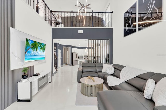 living room with ceiling fan and a towering ceiling