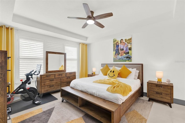 bedroom featuring ceiling fan, a tray ceiling, and light carpet