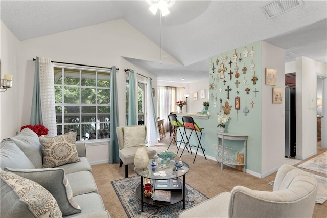 living room featuring ceiling fan, vaulted ceiling, a textured ceiling, and light carpet