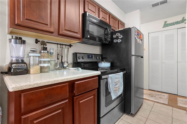 kitchen with light tile patterned floors, light stone counters, electric stove, and a textured ceiling