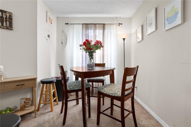 carpeted dining room with a textured ceiling