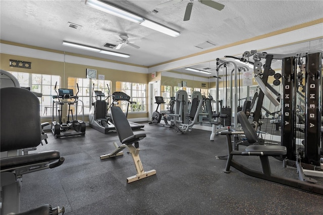 gym featuring ceiling fan, a wealth of natural light, and a textured ceiling