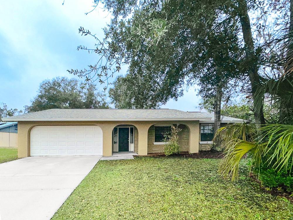 ranch-style house with a garage, stucco siding, concrete driveway, and a front yard