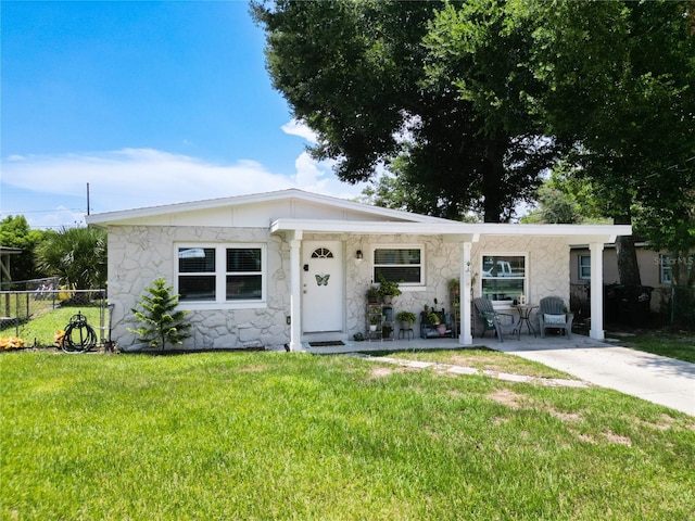 view of front of home featuring stone siding, fence, and a front lawn