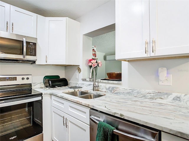 kitchen featuring white cabinetry, sink, stainless steel appliances, and light stone counters