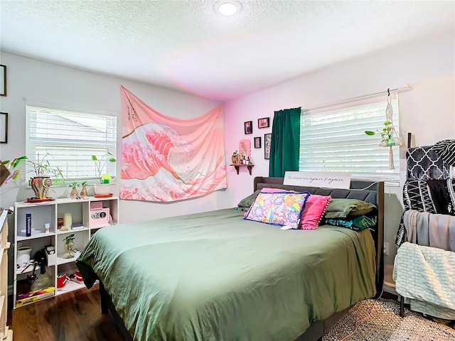 bedroom with a textured ceiling, hardwood / wood-style floors, and multiple windows