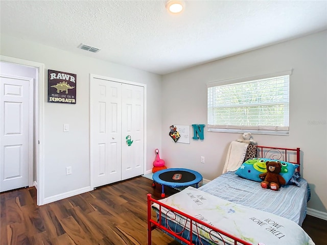 bedroom with a closet, dark wood-type flooring, and a textured ceiling