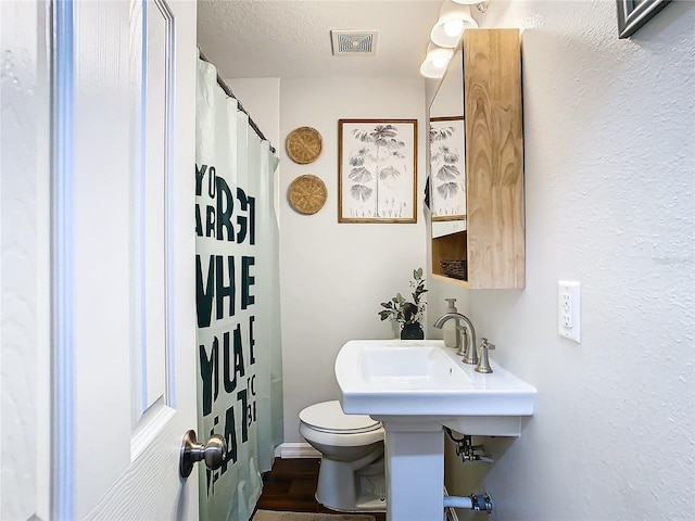 bathroom featuring hardwood / wood-style floors, toilet, and a textured ceiling