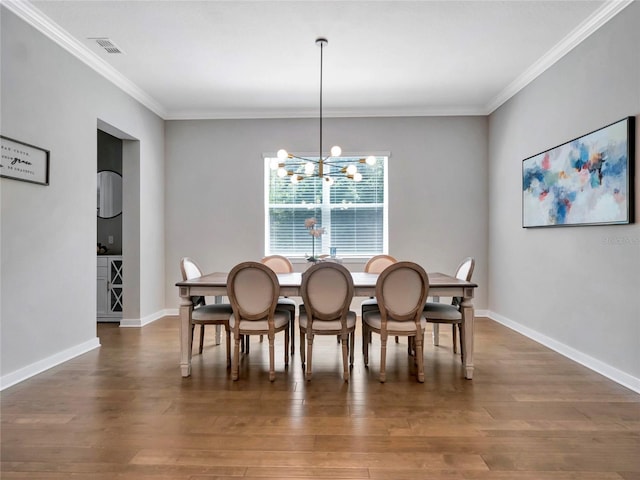 dining space featuring dark hardwood / wood-style flooring, ornamental molding, and an inviting chandelier