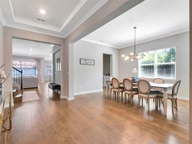 dining area with wood-type flooring, a healthy amount of sunlight, a notable chandelier, and ornamental molding