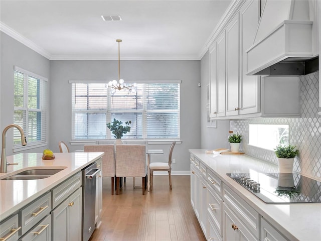 kitchen with sink, tasteful backsplash, custom range hood, pendant lighting, and black electric stovetop