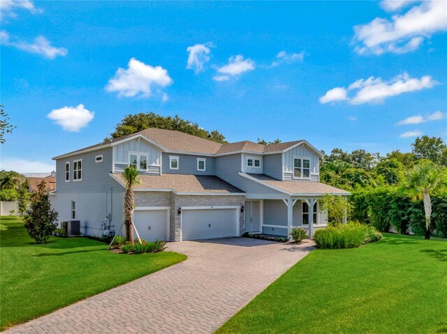 view of front of house featuring cooling unit, a garage, and a front yard