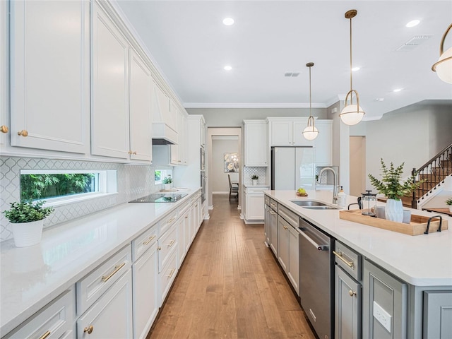 kitchen with pendant lighting, dishwasher, an island with sink, sink, and white cabinets