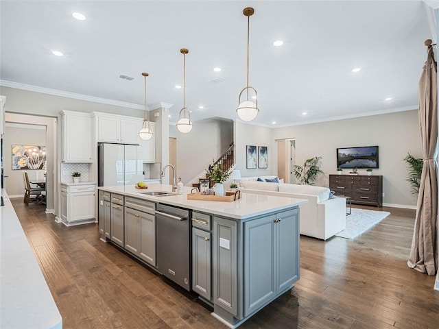 kitchen featuring sink, hanging light fixtures, a center island with sink, dishwasher, and white fridge